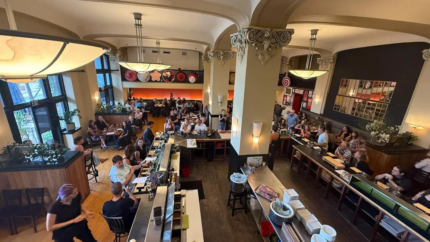 Guests sharing dinner while Hana’s team works behind the sushi counter in the Wilma Building