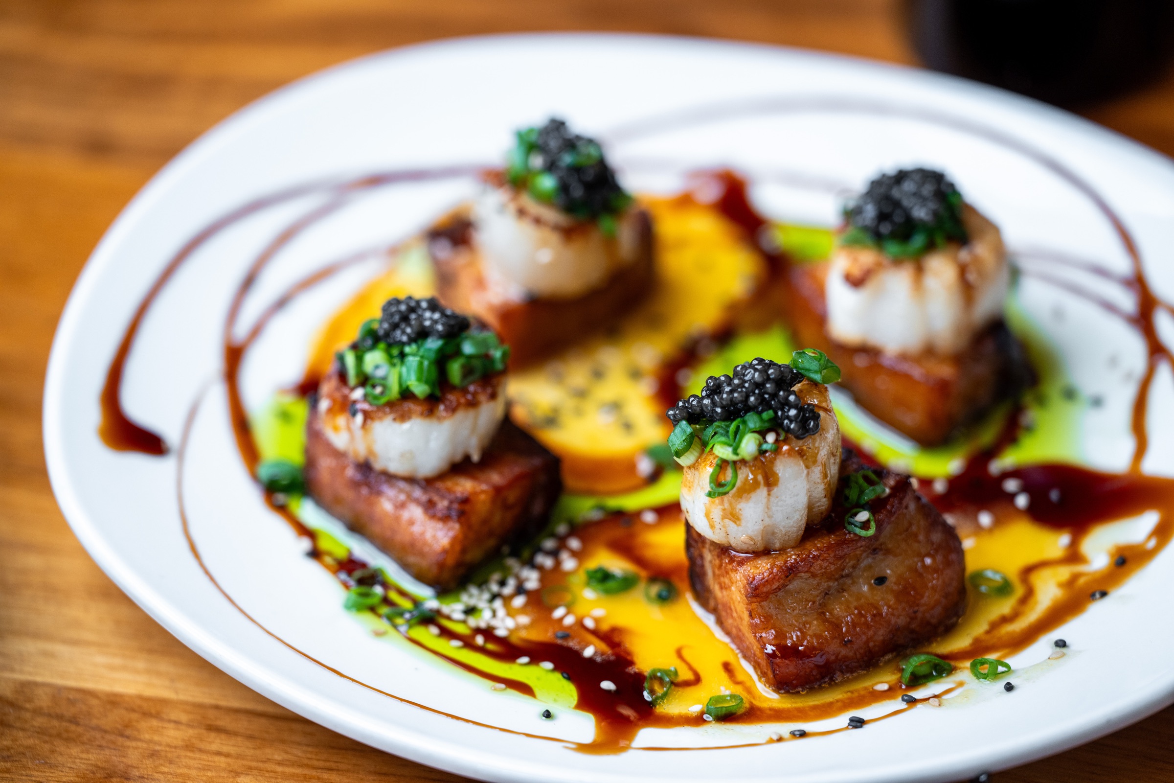 Seared scallops with roe and sauces on a white plate
